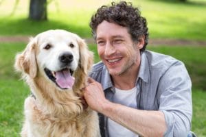 A man sits with his dog at the park.