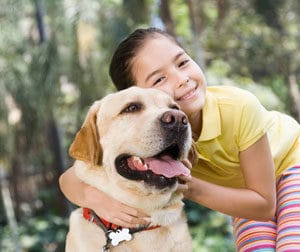 girl hugging yellow lab