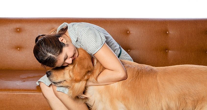 A girl gives her dog a hug before leaving on vacation.