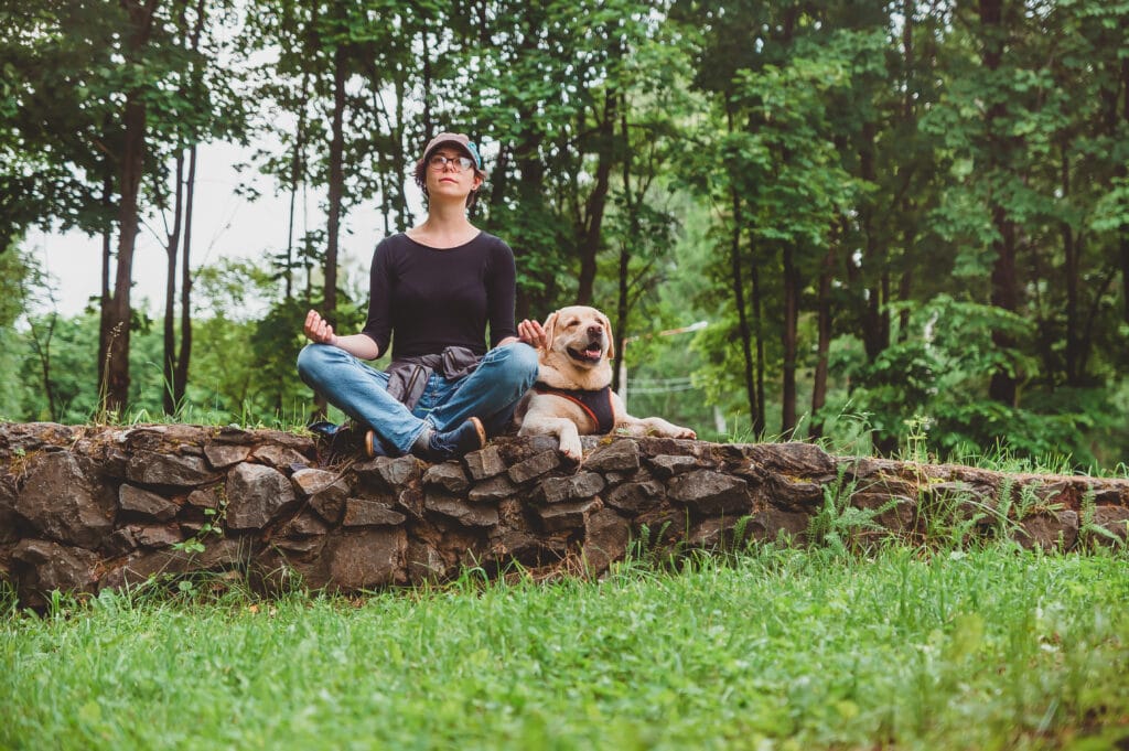 a girl meditates with her dog in a park