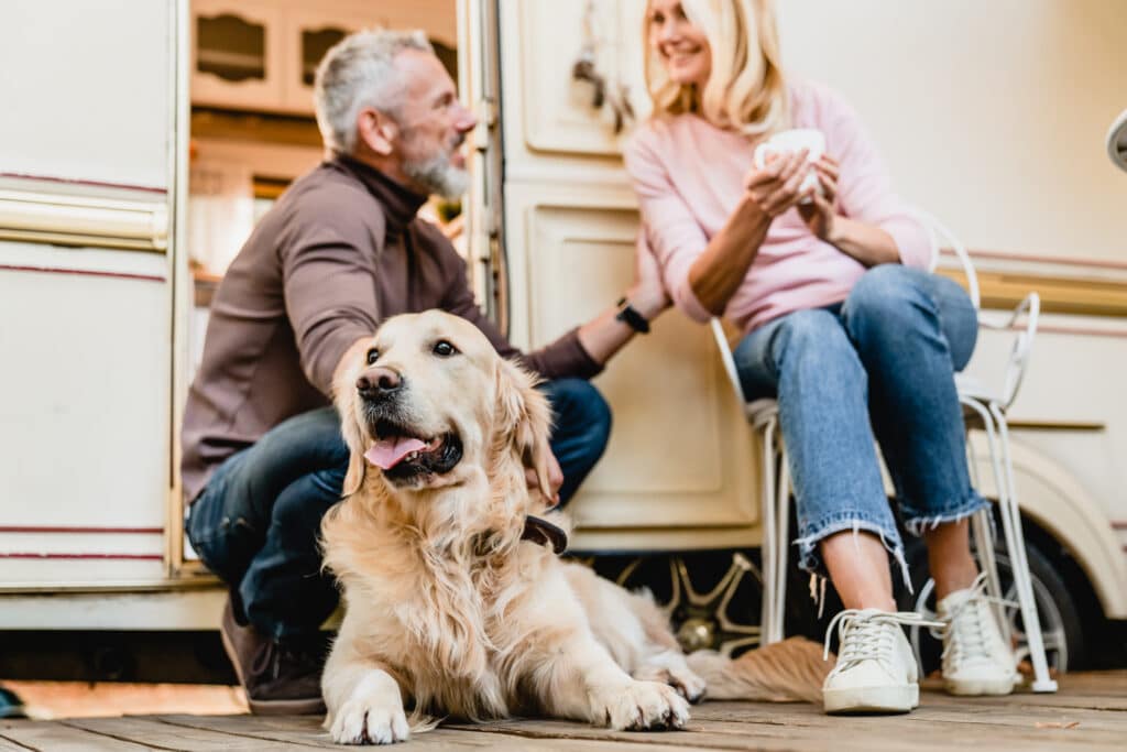 Husband and Wife enjoy camping trip with calm and relaxed dog outside