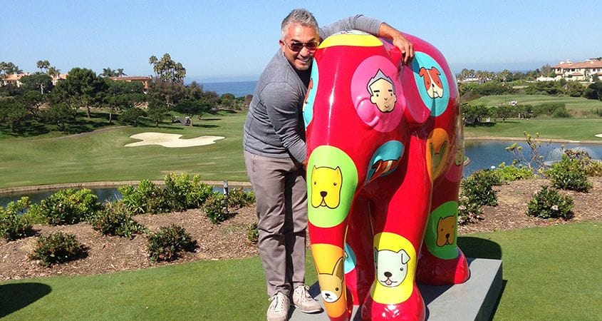 Cesar Millan hugs an interesting piece of artwork.